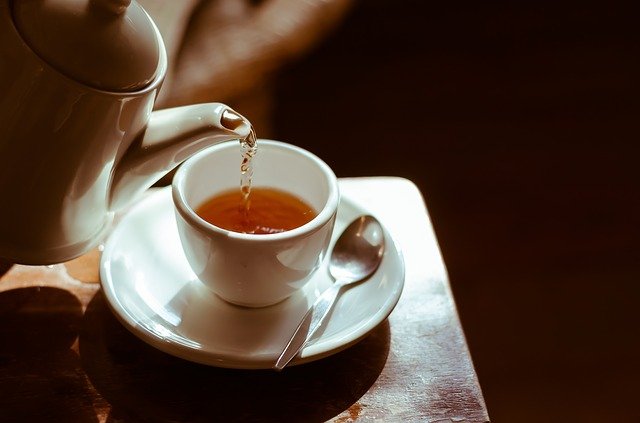 White tea in a glass cup surrounded by dried white tea leaves